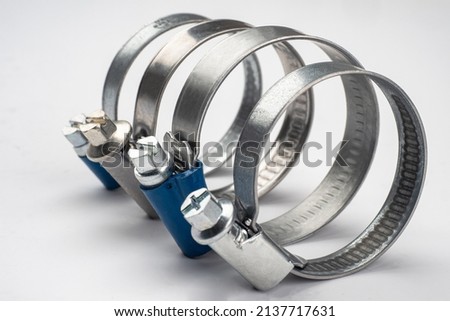 Metal clamps with different types of bolts. Small steel clamps on light background. Clamps designed for car repair. Concept of selling goods for auto repair. Metal hose clips close up.