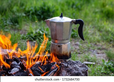 Metal coffee maker on an open fire in nature. Making coffee. Camping in summer.