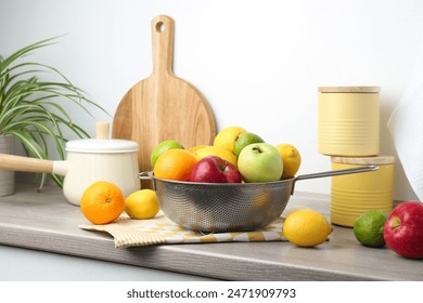 Metal colander with different fruits on countertop in kitchen - Powered by Shutterstock