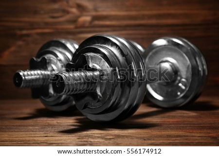 Metal collapsible dumbbells on wooden background, closeup