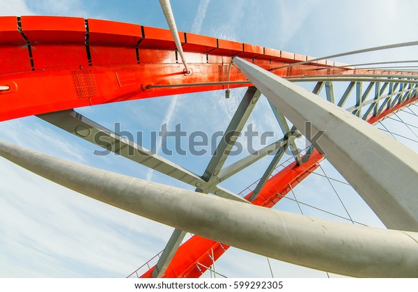 Metal construction of a bridge of red color against\
the sky