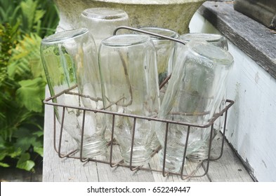 Metal Crate Of Glass Antique Milk Bottles On Steps Of Old House 