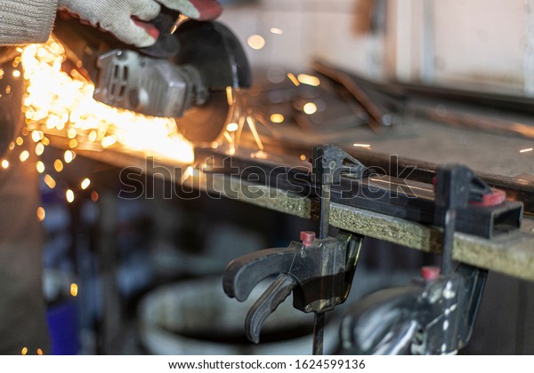 Metal cutting. Grinding\
steel. Work as a grinder. Sparks from friction. Men\'s work.\
Creating a design. The project in the workshop. Iron processing.\
Hand electric tool.