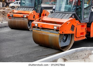 The metal cylinders of the large vibratory rollers forcefully compact the fresh asphalt of the road surface. Copy space.