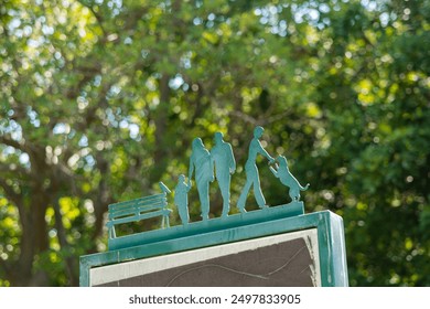 Metal decorative elements with people silhouettes: family with a child, person with a dog, bird on a bench. Family leisure in the park concept. Beautiful bokeh in the background. Copy space - Powered by Shutterstock