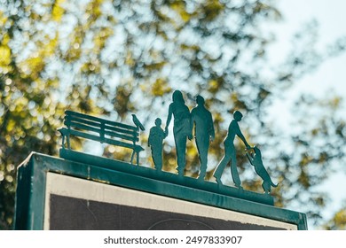 Metal decorative elements with people silhouettes: family with a child, person with a dog, bird on a bench. Family leisure in the park concept. Beautiful bokeh in the background. Copy space - Powered by Shutterstock