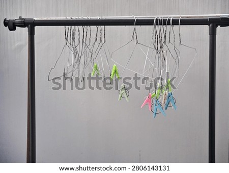 A metal drying rack with clips and clothes hangers against a gray background. Common laundry drying equipment.