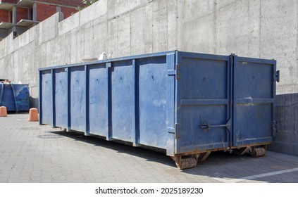 Metal Durable Blue Industrial Trash Bin For Outdoor Trash At Construction Site. Large Waste Basket For Household Or Industrial Waste. A Pile Of Waste