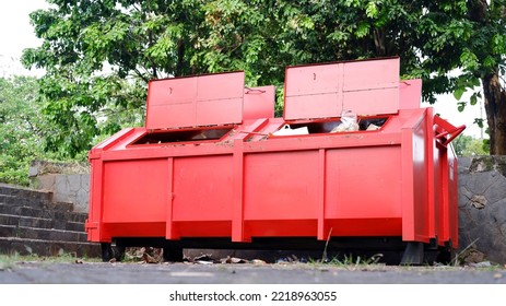 Metal Durable Orange Industrial Trash Bin For Outdoor Trash At Construction Site. Large Waste Basket For Household Or Industrial Waste. A Pile Of Waste