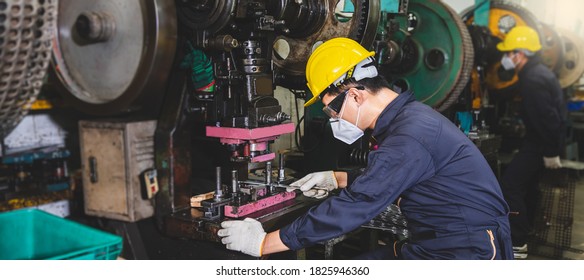 Metal Factory Workers Wearing A Face Mask And Gloves Are Working To Manufacture Metal Parts With Lathes Inside An Industrial Facility.