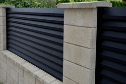 Metal Fillings Of The Fence With An Underlay Of Concrete Blocks. A Metal Aluminum Fence Will Provide Privacy Around The Garden. Horizontal Slats Cover Well. A Hedge Made Of Tuji Adds Protection