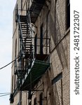 a metal fire escape, with shadows, on the outside wall of a brick building on a sunny day