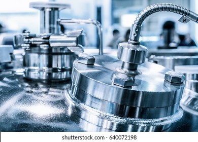 Metal flanges with flexible nipples, chemical reactor body, selective focus. Abstract industrial background.
