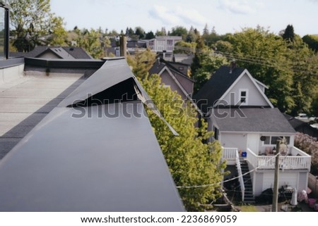 Metal flashing roof corner damage after wind storm. Metal flashing lifted or blown up. Repair needed for waterproofing. Roof repair on flat roof with a modified bitumen roofing system. Selective focus