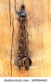 Metal forged shackles on a chain hanging on a wooden wall