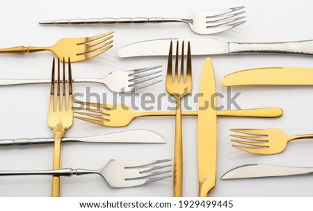 Metal forks and knives on a white table. gold and silver cutlery set