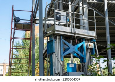 The Metal Frame Of The New Building With Insulation And Sandwich Panels. Construction Elevator, Electric Lifting Platform For Lifting Workers To A Height. Modern Construction Technologies