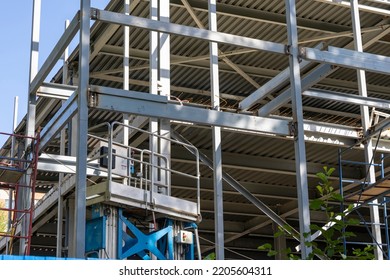 The Metal Frame Of The New Building With Insulation And Sandwich Panels. Construction Elevator, Electric Lifting Platform For Lifting Workers To A Height. Modern Construction Technologies