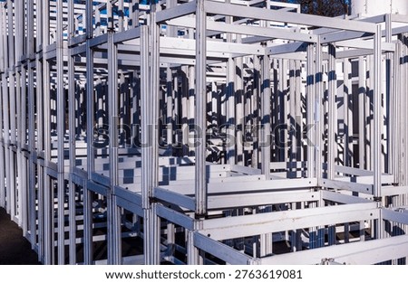 Metal framework with interconnected square sections creating a complex grid pattern, offering deep perspective and strong light and shadow plays in an outdoor setting