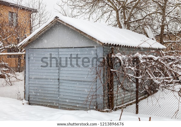 Metal garage in winter\
during a snowfall