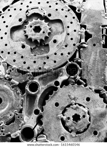 Metal gears and other car parts welded together in a\
design.  Black and white photo of machine auto parts taken in June\
2019 in Richmond, Va.
