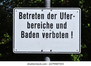 Metal German Sign Beside Public Bathing Pool Translated as 'Entering the shore areas and bathing are prohibited'  - Shutterstock ID 2279487555