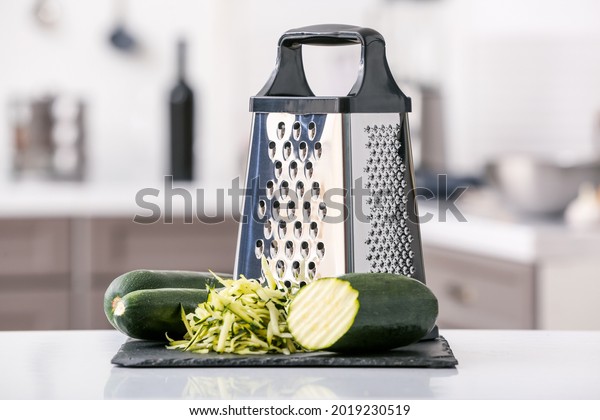 Metal grater and\
zucchini on kitchen table