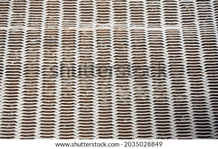 Metal grid with cells of complex shape forms a structured abstract background in the grunge style. Rhythmic alternation of light and dark geometric shapes.
