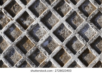 Metal grid surface texture. Square pattern industrial background. Rough weathered material detail. Urban infrastructure closeup. Repeating geometric structure. Abstract metal surface.