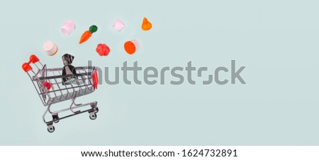 Metal grocery shopping basket, shopping car with products flying into it on light blue background, isolated, banner. Concept of shopping, sales