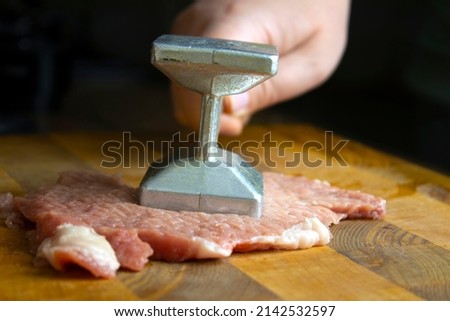 Metal hammer for beating meat with meat on a wooden board