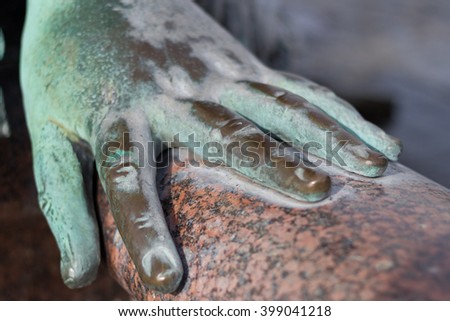 metal hand of an old bronze statue laying on 