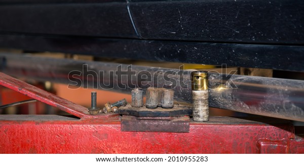 Metal heads of a\
pneumatic socket wrench on the lift support. In the garage, a man\
changes parts on a vehicle. Small business concept, car repair and\
maintenance service. 