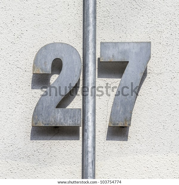 metal house number twenty-seven, divided by a\
vertical pipe.