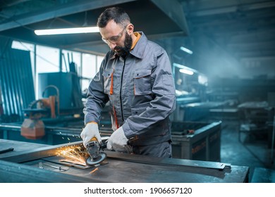 Metal industry worker dressed in work wear doing some metalwork, grinding steel product at the factory. Handsome artisan at the manufacturing of metal products. High quality photo - Powered by Shutterstock