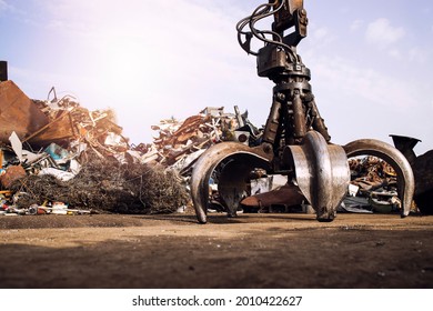 Metal junk yard with hydraulic lifting machine with claw attachment for scrap metal lifting. - Powered by Shutterstock