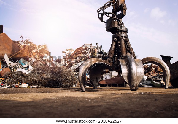 Metal junk yard with hydraulic\
lifting machine with claw attachment for scrap metal\
lifting.