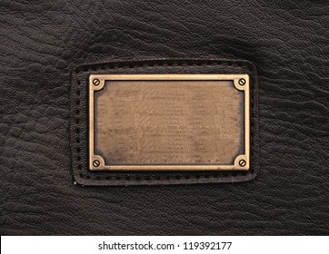 Metal Label On Old Black Leather Background