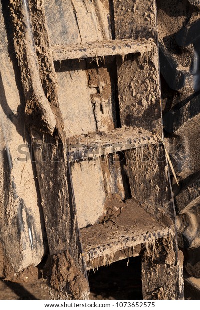 metal ladder on a tractor or other agricultural\
machinery, completely dirty and covered with a thick layer of mud,\
closeup