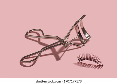 A Metal Lash Curler With False Lashes Composition On Pink Background