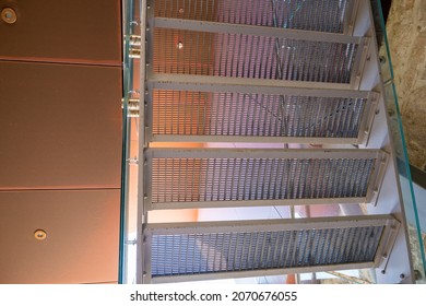 Metal Lattice Staircase Clad With Glass On The Background Of Copper Ceiling Tiles