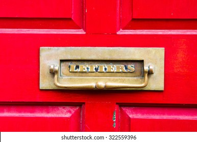 A Metal Letterbox In A  Red Wooden Door