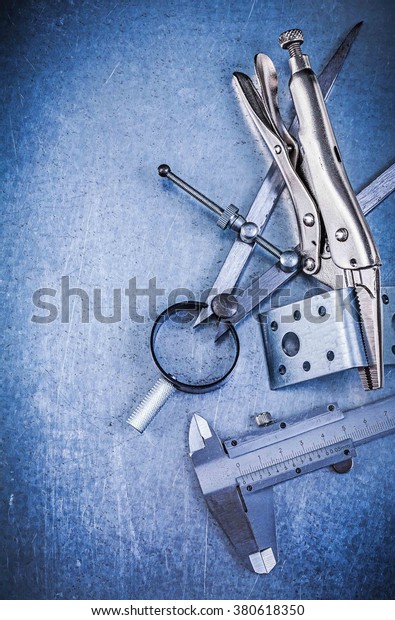 Metal lock jaw\
pliers trammel caliper drilled angle bars construction drawing\
compass on metallic\
background.