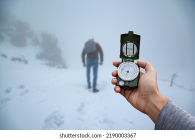 A Metal Magnetic Compass In The Hand Of A Traveler Against The Snow Mountains