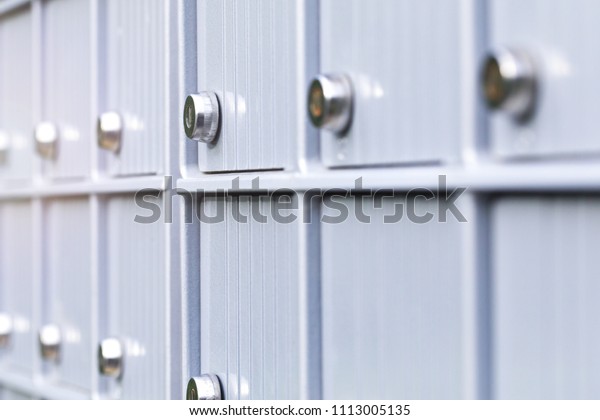 Metal mailboxes and lock in business center of\
an urban neighborhood. Mail boxes in rows at entrance of modern\
building. Security storage mailroom for secret files or corporate\
postal service.