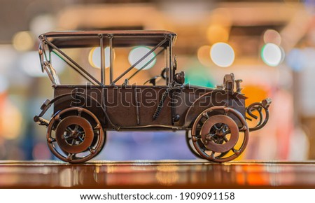 Metal model toy of a retro car stands on a wooden surface on a bright abstract background