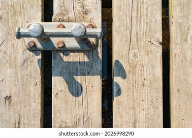 A Metal Mooring Bollard And Its Shadow On An Old Wooden Dock. Background. View From Above. 