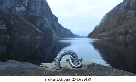 Metal mooring hook on a dock with a serene lake and dramatic mountains in the background. Soft lighting enhances the natural beauty and calm water reflections. Perfect for travel or nature themes. - Powered by Shutterstock