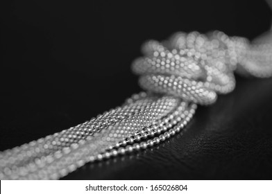 Metal necklace on the black background, tied in the knot - Shutterstock ID 165026804