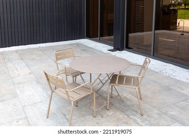 Metal Outdoor Round Table And Three Chairs On A Stone Slab. Beige Outdoor Furniture